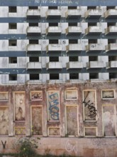 Abandoned building with graffiti on a dilapidated façade and blue, white, textured concrete