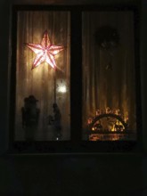 A dark window with a glowing star and interior shadows, Christmas lights, Thuringian Forest,