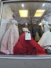 Shop window with festive clothes and mannequins wearing masks during corona, elegant ambiance,