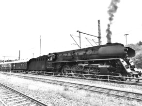 Historic steam locomotive pulls wagons onto tracks, smoke rises, Upper Franconia