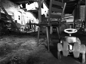 Abandoned industrial space with an old chair and a toy car on the floor, black and white, Upper