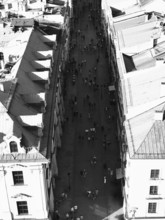 Aerial view of busy street between tall buildings in sunny atmosphere, black and white, Krakow,