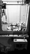 View of a claw machine filled with stuffed animals in a play area, black and white, Batumi, Georgia