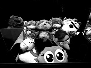 Collection of various stuffed animals in a dark environment, black and white photo of a toy vending