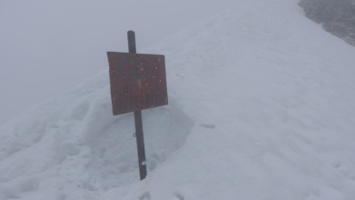 Snowy area with a red sign in thick fog