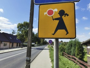 Road sign depicting a stylized person holding a candy on a sunny day, Poland