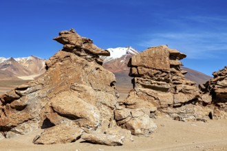 Majestic rock formations in a vast, barren desert landscape under blue skies, The Altiplano