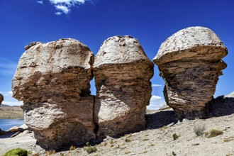 Three monumental rocks stand proudly in a dry desert landscape under clear blue skies, The