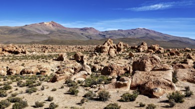 Rocky desert landscape with impressive rock formations and mountains under a blue sky, The