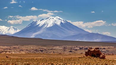 Snowy mountain in front of a vast desert panorama under clear, blue sky, the landscape of the