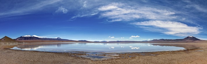 Wide and open landscape with a lake under dramatic skies and distant mountains, The Laguna Colorada