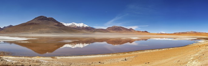 Extensive landscape with reflecting lake and snow-capped mountains under bright skies, Laguna