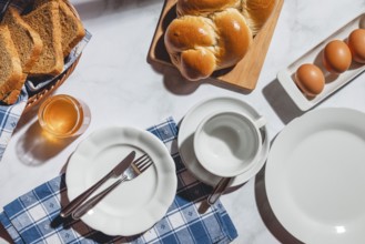 Breakfast items such as toast, stollen, eggs and honey on a white table