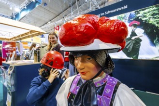 Tradition and progress. A young trade fair visitor wearing 3D glasses next to a model of a woman