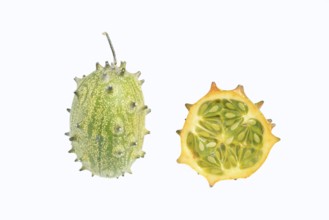 Horned cucumber, kiwano or horned melon (Cucumis metuliferus), whole and sliced fruit on a white
