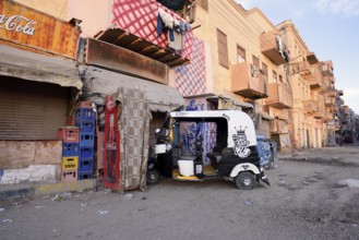 Street and a parked tuk-tuk in front of a shop, Esna, Egypt
