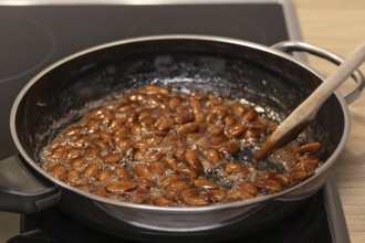 Almonds caramelized in a pan while stirred with a spoon. Germany