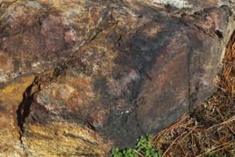 Close-up of outcrop rock surface with nuanced rusted, yellowish, reddish brown and blackened colour