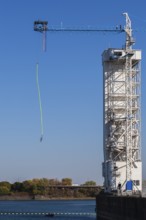 Montreal Bungee Tower with male bungee jumper in midair with his ankles tied to a long yellow