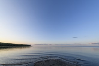 Far-reaching view of the quiet lake Vänern with gently sloping granite rocks archipelago under calm