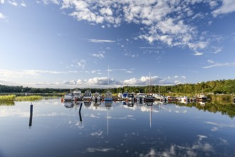 Several boats are moored in the quiet pleasure boat harbor of Ekenäs, water reflects the sky,