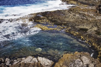 Rocky coastline with clear turquoise water pools and nearby waves, Yaiza Lanzarote