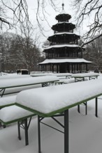 Winter in the English Garden, snow-covered beer garden tables and benches, Chinese Tower, Munich,