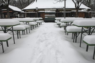 Winter in the English Garden, snow-covered beer garden tables and benches, Munich, Bavaria, Germany