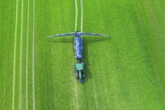 Aerial view over tractor towed liquid manure spreader, slurry spreader enabling the fertilization