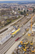 Aerial view of a construction site with a yellow train on the tracks and construction cranes,
