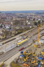 Aerial view of a city with a construction site and a yellow train on the tracks, construction