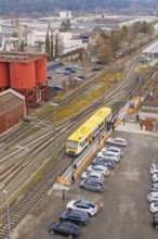 Aerial view of a train station with a yellow train surrounded by parking lots and industrial