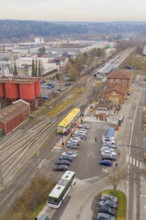 Rural area with a yellow train on the rails, surrounded by meadows and farmhouses, taking the