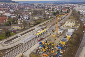 Construction site in urban area with yellow train and crane, surrounded by residential buildings,