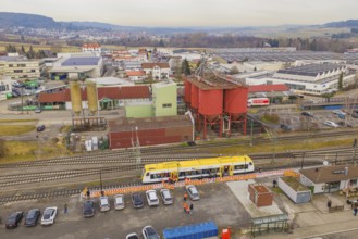 Aerial view of an industrial area with yellow train and large building structures, acceptance of
