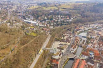 Panoramic picture of a city with river and railroad tracks, surrounded by wooded hills, acceptance