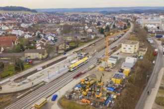 Aerial view of a railway station under construction with cranes and a yellow train, urban