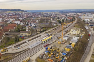 Aerial view of urban construction site with yellow train on tracks and residential buildings,