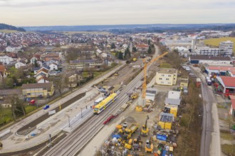 City view with train station and construction sites, surrounded by houses and a yellow train,