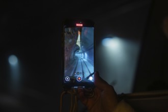 A smartphone shows a picture of a tunnel with rails, the Hermann Hesse Railway, Calw, Black Forest,