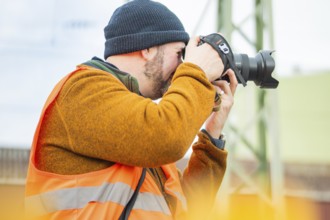 A photographer wears a safety vest and takes pictures at work, taking the Hermann Hesse Railway,