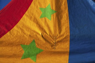 Close-up of two green stars on dyed red, yellow and blue canvas cloth material, Quebec, Canada