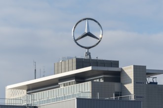 Architecturally modern building with Mercedes-Benz logo and slightly cloudy sky, Mercedes Star,