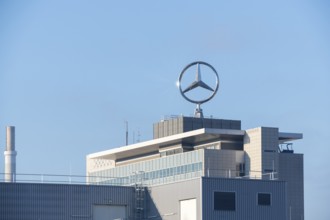 Close-up of a building with prominent Mercedes logo and chimney under a blue sky, Mercedes Star,