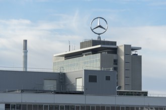 Tall, modern factory building with Mercedes logo in cloudy sky, Mercedes Star,