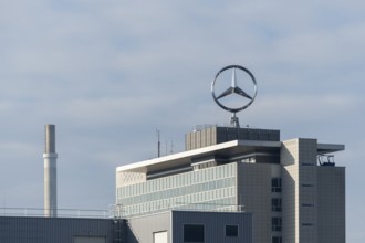 Large Mercedes-Benz logo on roof of an industrial building under grey sky, Mercedesstern,