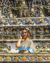 Young woman in traditional clothing presents herself to photographers, Wat Arun Buddhist temple,
