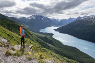 Female mountaineer enjoying views of blue lake and mountains on Twin Peaks Trail, Eklutna Lake,