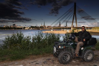 A man on an ATV on the banks of the Düna near the Vansu Bridge, Riga, Düna, Latvia
