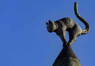 Lead sculpture of a cat on the roof of the cat house against a clear sky, Riga, Latvia